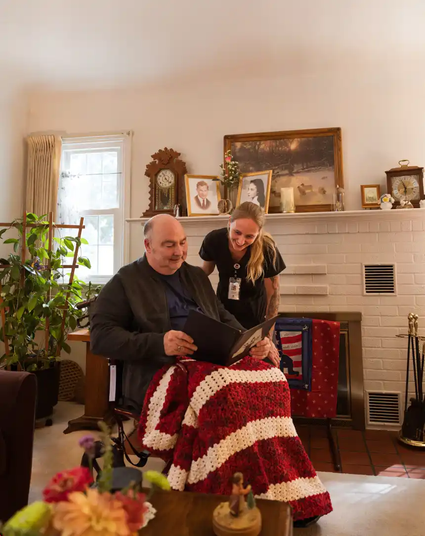 Hospice caregiver looking through a photo album with a patient at home